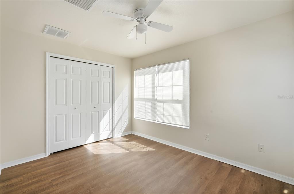 5002 Beechcraft Way Seffner, FL 33584 - Photo 12 of 26 an empty room with wooden floor ceiling fan and windows