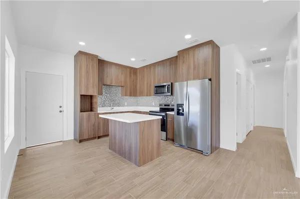 a kitchen with kitchen island granite countertop wooden cabinets a refrigerator and a sink