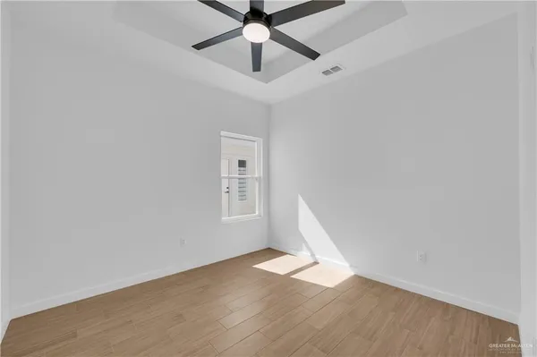 a view of empty room with wooden floor and fan