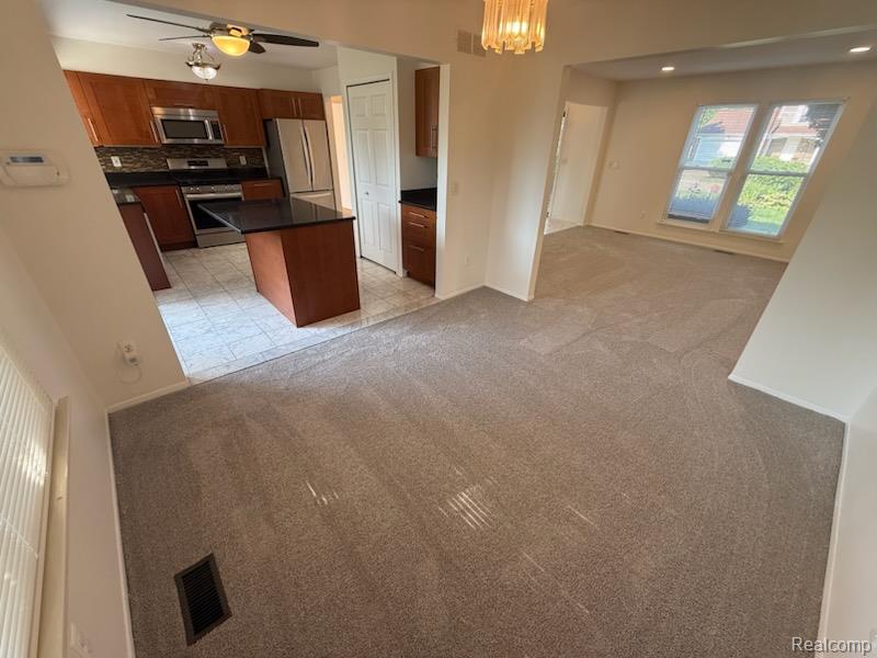 28144 Yorktown Road Farmington, MI 48331 - Photo 4 of 25 Open-concept living space featuring new gray carpeting and a kitchen with warm wood cabinetry