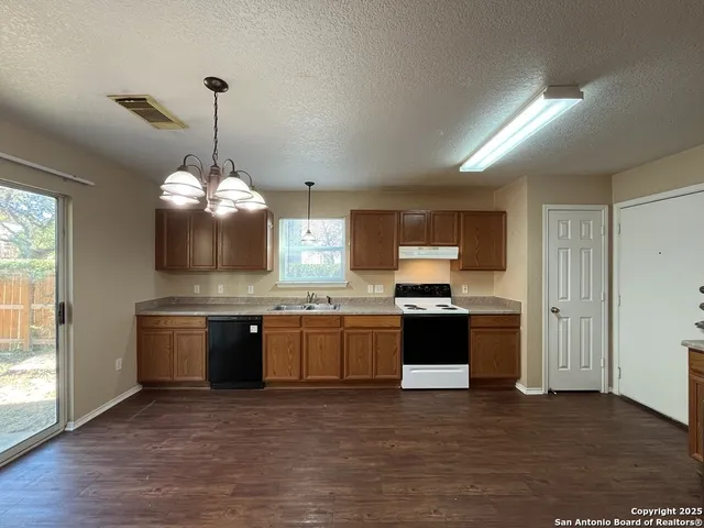 a large kitchen with stainless steel appliances granite countertop a stove and a chandelier