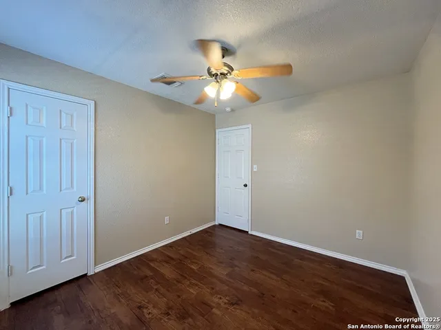 a view of an empty room and chandelier fan