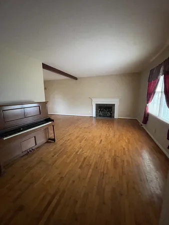 an empty room with wooden floor cabinet and windows