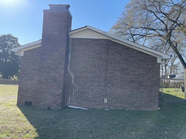 a brick house with a small yard and large trees