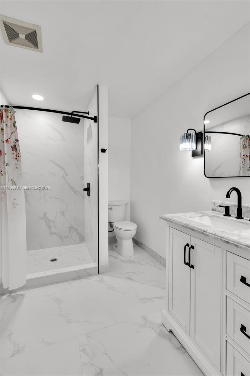 6031 Southwest 82nd Avenue Miami, FL 33143 - Photo 22 of 42 a bathroom with a granite countertop sink a toilet and shower