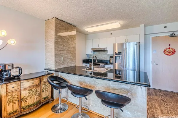 a kitchen with stainless steel appliances granite countertop a stove a refrigerator and a view of living room