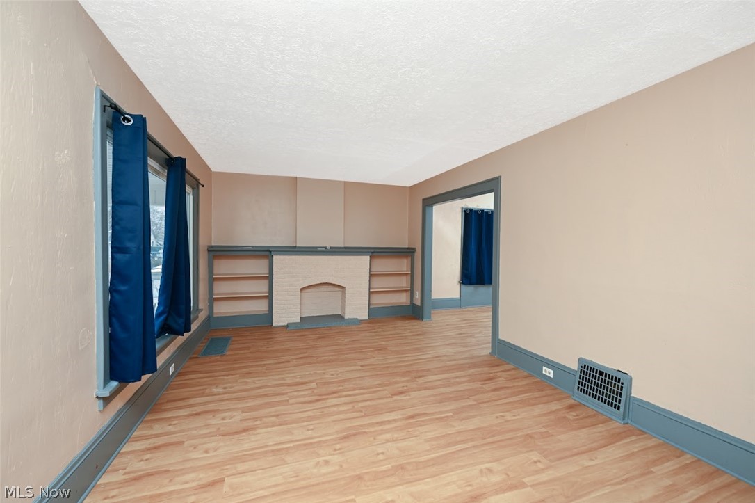 77 West Mildred Avenue Akron, OH 44310 - Photo 5 of 40 Unfurnished living room featuring light wood-style floors, a textured ceiling, and a fireplace