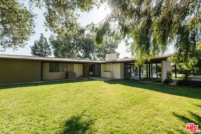 a front view of a house with a yard and trees