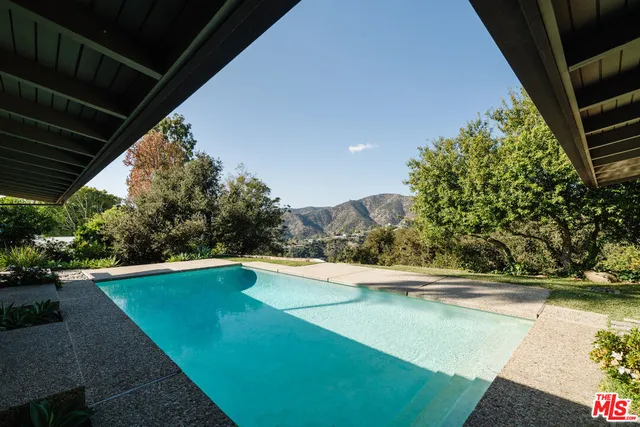 a view of a backyard with lawn chairs under an umbrella