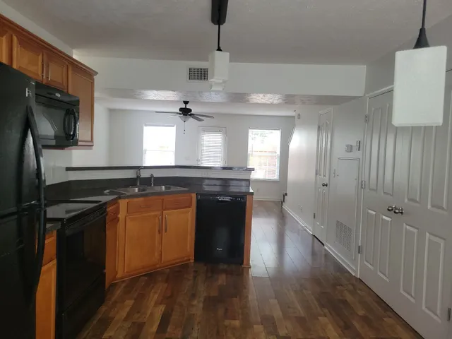 a kitchen with stainless steel appliances granite countertop a refrigerator a sink dishwasher a stove and white countertops with wooden floor