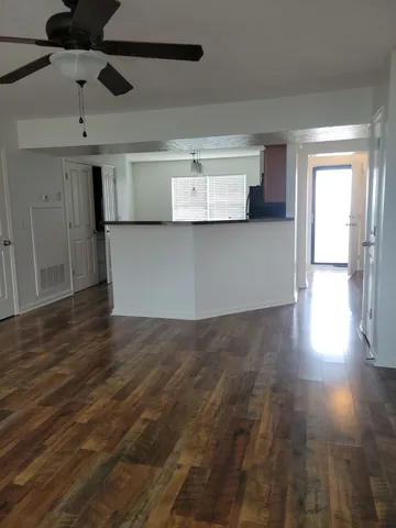 a view of a room with wooden floors and ceiling fan