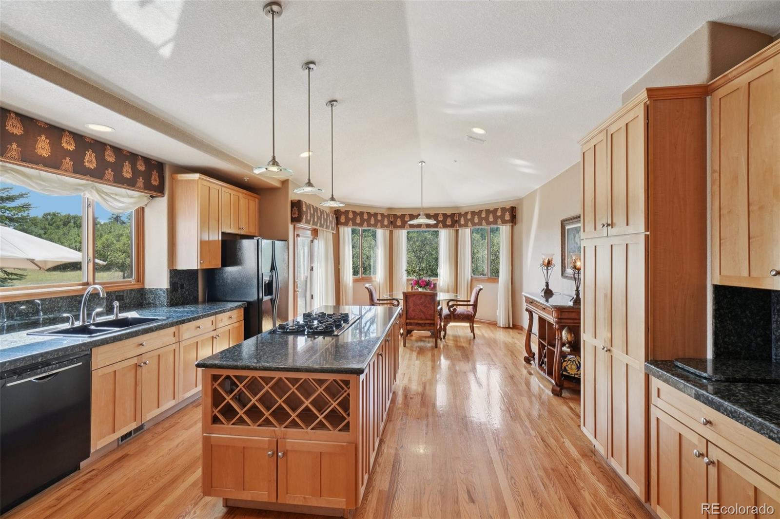 1475 Elk View Road Larkspur, CO 80118 - Photo 14 of 45 a open kitchen with stainless steel appliances granite countertop a stove a sink dishwasher a refrigerator with wooden floor and cabinets