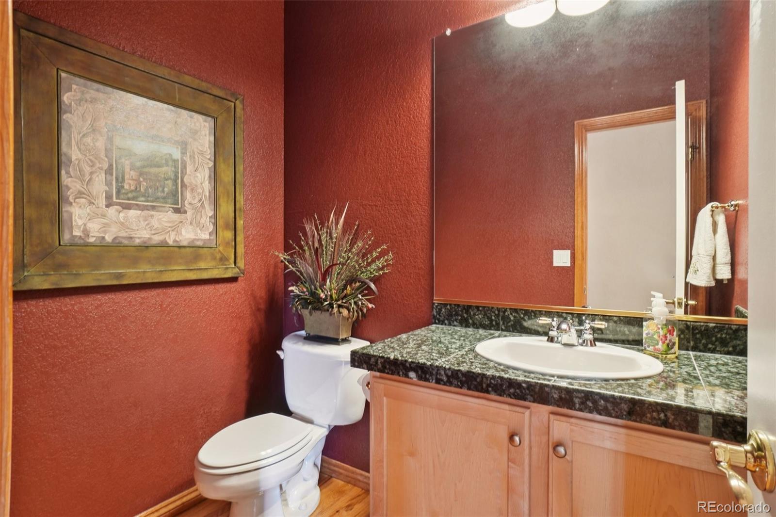 1475 Elk View Road Larkspur, CO 80118 - Photo 15 of 45 a bathroom with a granite countertop toilet a sink and a mirror