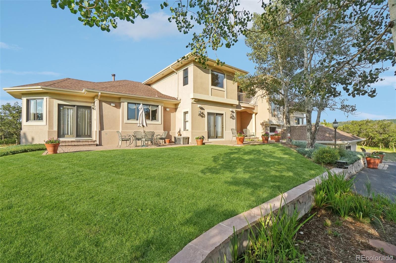 1475 Elk View Road Larkspur, CO 80118 - Photo 2 of 45 a front view of a house with a garden and trees