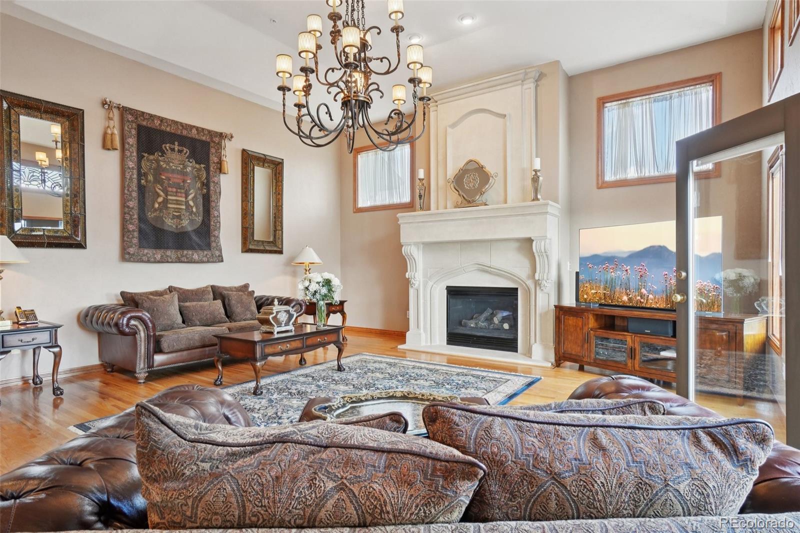 1475 Elk View Road Larkspur, CO 80118 - Photo 8 of 45 a living room with furniture a chandelier and a fireplace