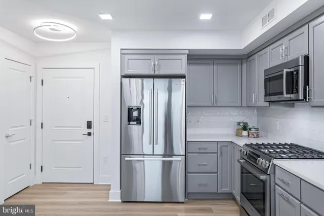 a kitchen with stainless steel appliances a sink a stove a microwave a refrigerator and cabinets