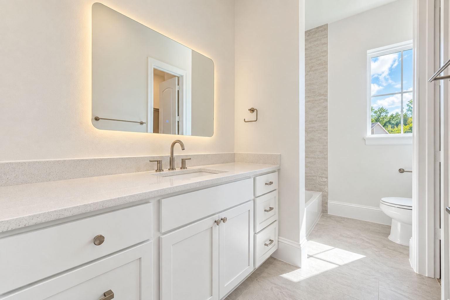2311 Hollister Road Houston, TX 77080 - Photo 32 of 46 Beautifully finished secondary bath featuring an extended vanity with generous cabinetry, quartz countertops, sleek fixtures, and a statement illuminated mirror. A glass-enclosed shower and natural light complete the fresh, sophisticated design, creating a polished retreat for family or guests.