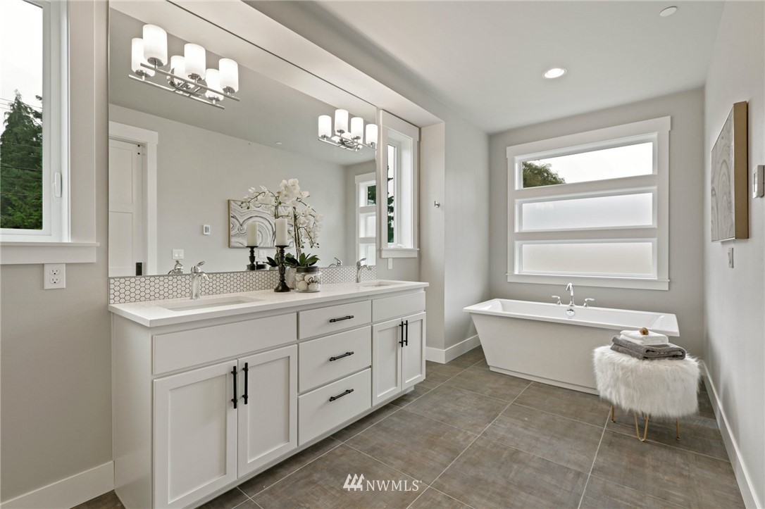 1430 236th Street Southeast Bothell, WA 98021 - Photo 30 of 38 a bathroom with a double vanity sink a mirror a bathtub and next to a window