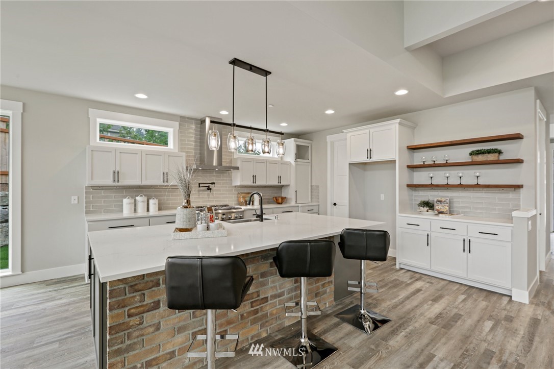 1430 236th Street Southeast Bothell, WA 98021 - Photo 9 of 38 a kitchen with stainless steel appliances kitchen island granite countertop a sink cabinets and wooden floor