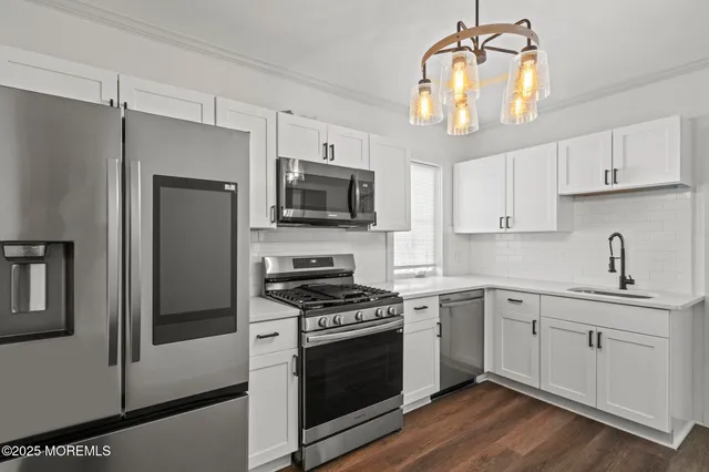 a kitchen with cabinets stainless steel appliances and wooden floor