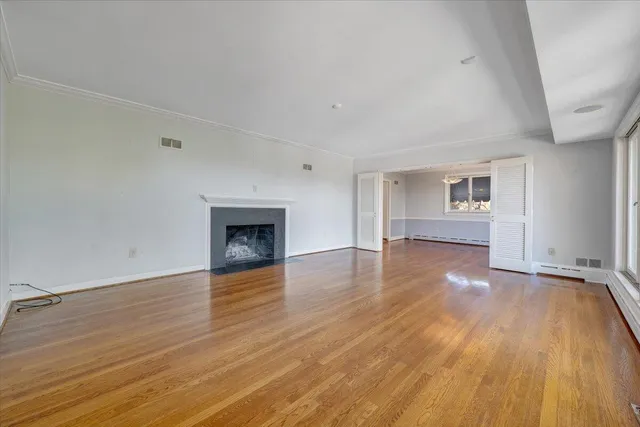 an empty room with wooden floor fireplace and windows