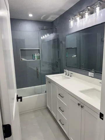 a bathroom with a double vanity sink a mirror and a bathtub