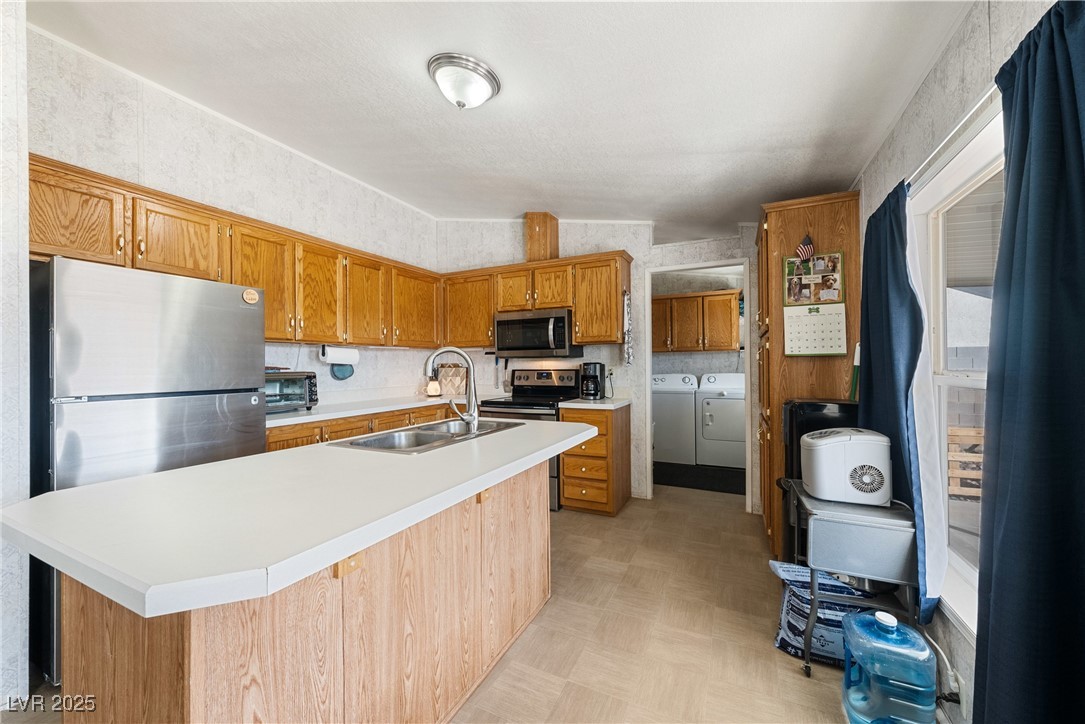 633 East Simkins Road Pahrump, NV 89060 - Photo 10 of 25 Kitchen with a sink, washer and dryer, light countertops, appliances with stainless steel finishes, and a center island with sink