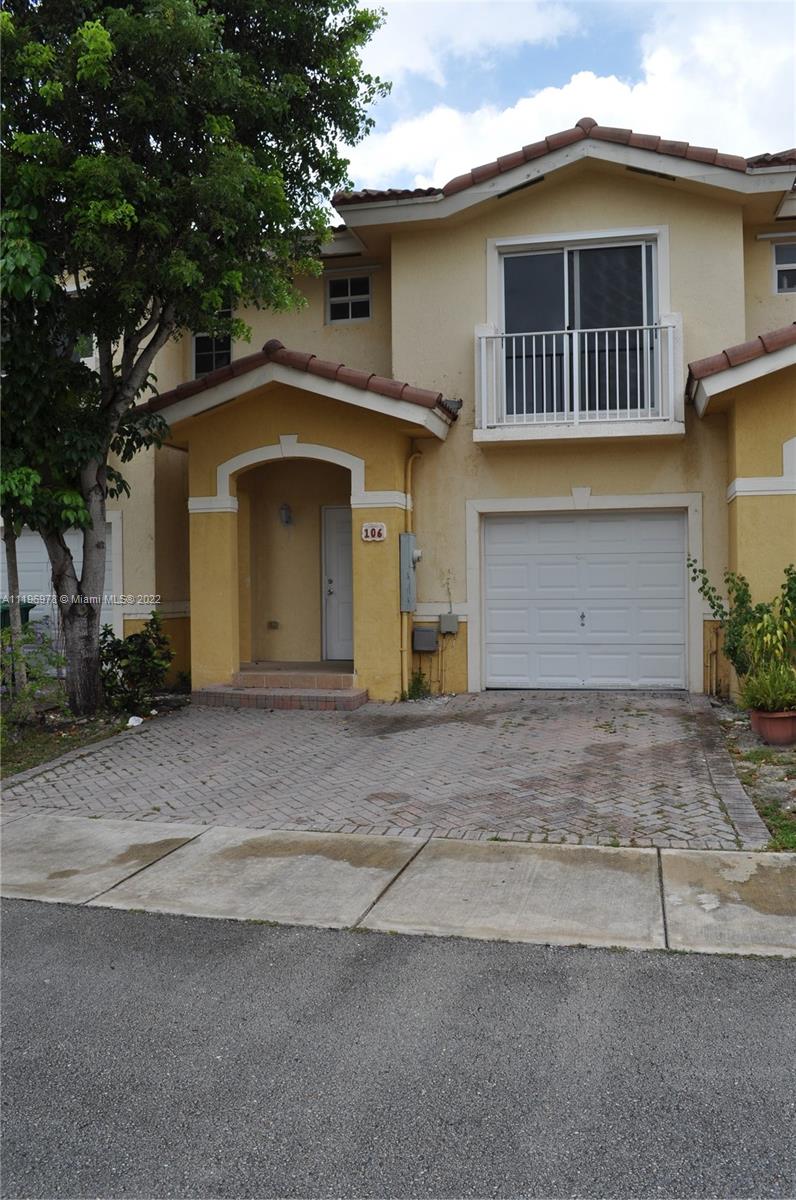 14086 Southwest 260th Street, Unit 106 Homestead, FL 33032 - Photo 1 of 26 a front view of a house with a yard and garage