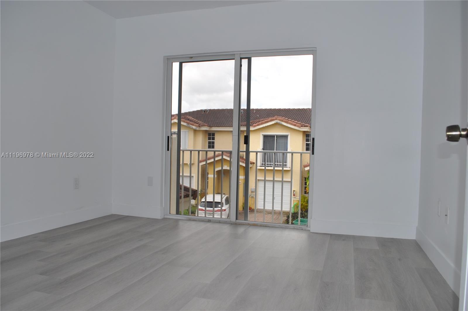 14086 Southwest 260th Street, Unit 106 Homestead, FL 33032 - Photo 22 of 26 an empty room with wooden floor and windows