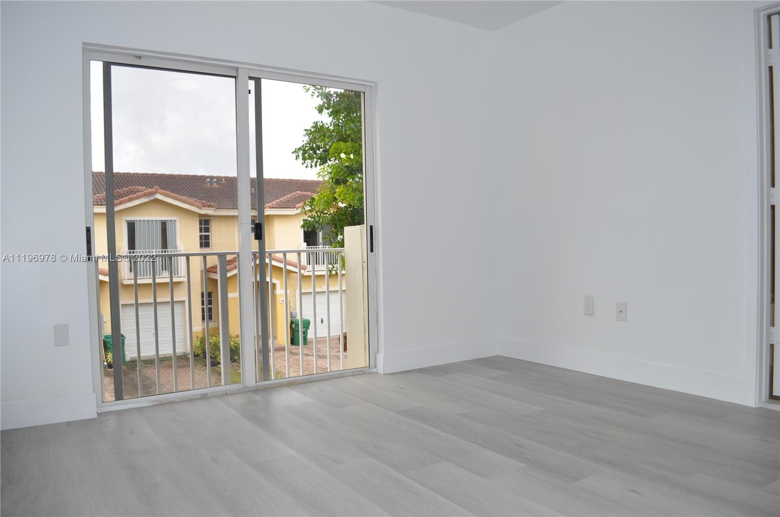 14086 Southwest 260th Street, Unit 106 Homestead, FL 33032 - Photo 24 of 26 an empty room with wooden floor and windows