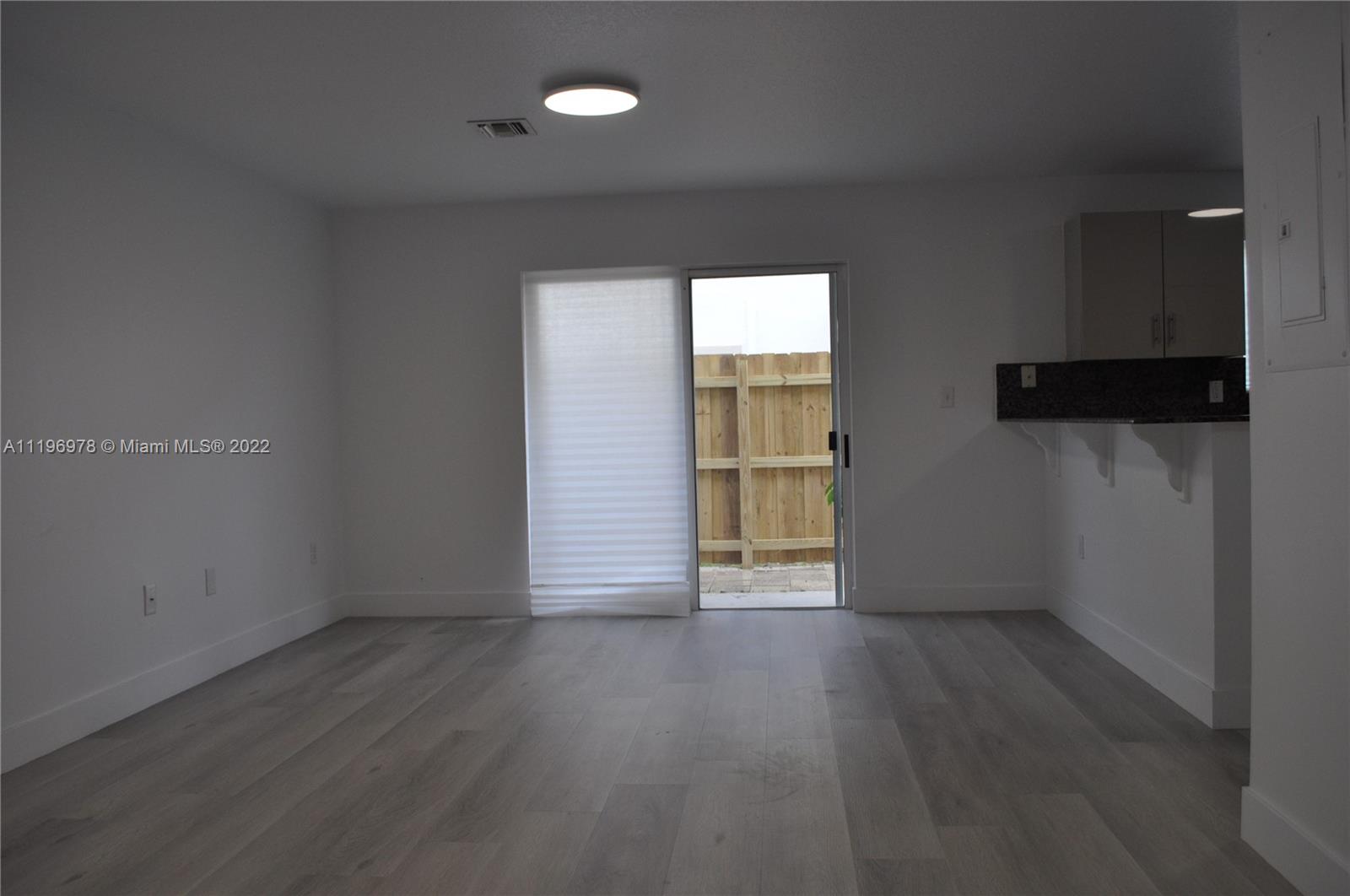 14086 Southwest 260th Street, Unit 106 Homestead, FL 33032 - Photo 5 of 26 an empty room with wooden floor and windows