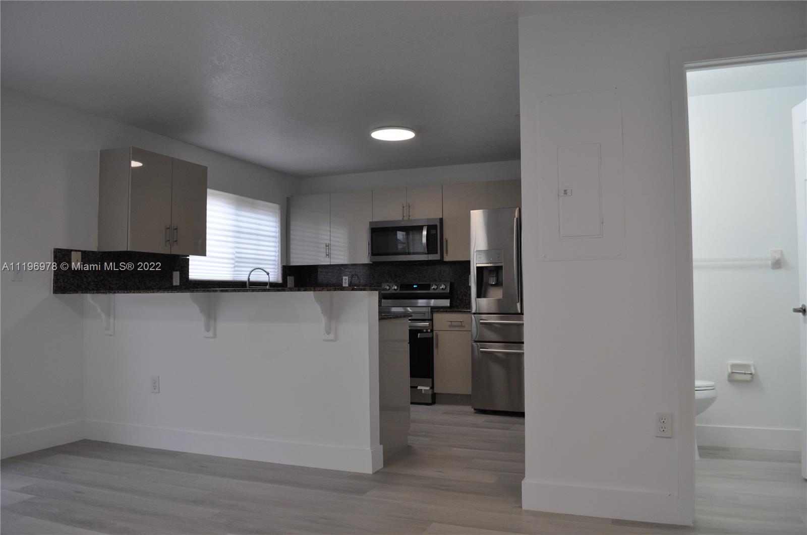 14086 Southwest 260th Street, Unit 106 Homestead, FL 33032 - Photo 7 of 26 a kitchen with stainless steel appliances granite countertop a refrigerator a sink a stove and oven with wooden floor