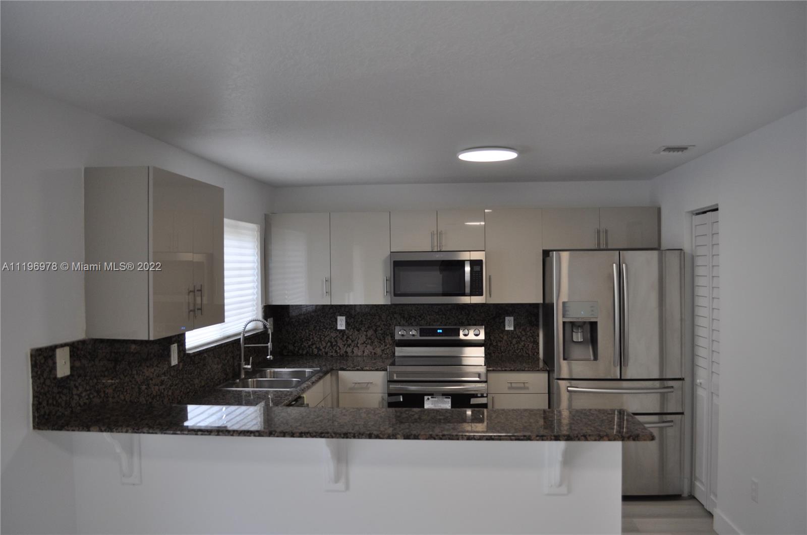 14086 Southwest 260th Street, Unit 106 Homestead, FL 33032 - Photo 8 of 26 a kitchen with stainless steel appliances a refrigerator and a stove top oven