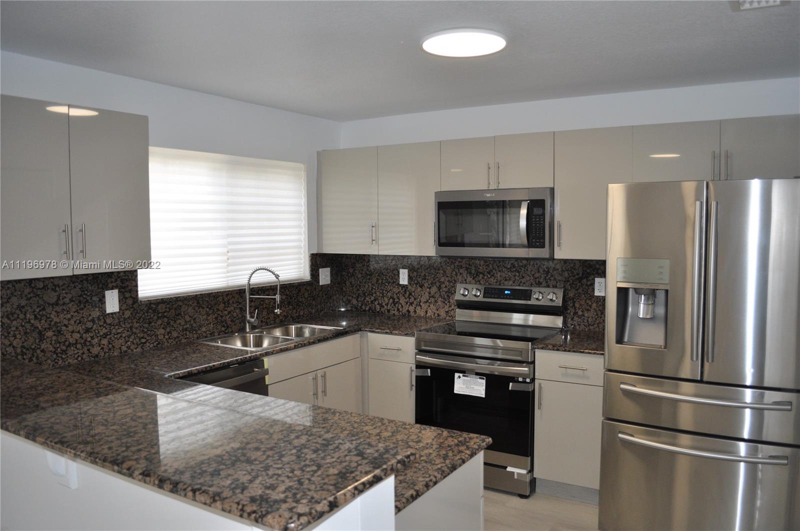14086 Southwest 260th Street, Unit 106 Homestead, FL 33032 - Photo 9 of 26 a kitchen with stainless steel appliances granite countertop a sink stove microwave and refrigerator