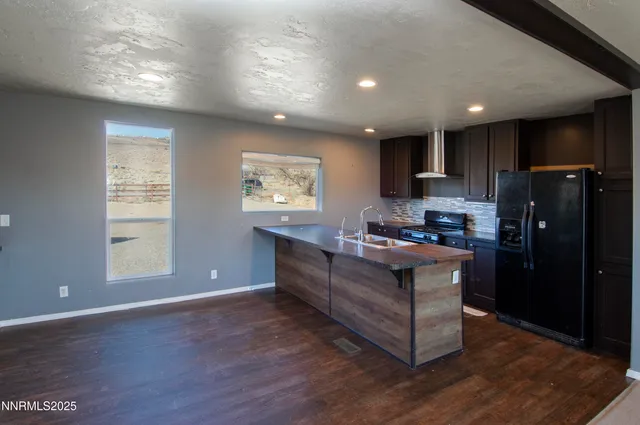 a view of an empty room with a chandelier fan and kitchen view