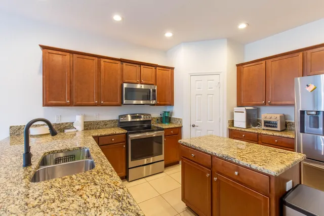 a kitchen with granite countertop a stove a sink and a microwave