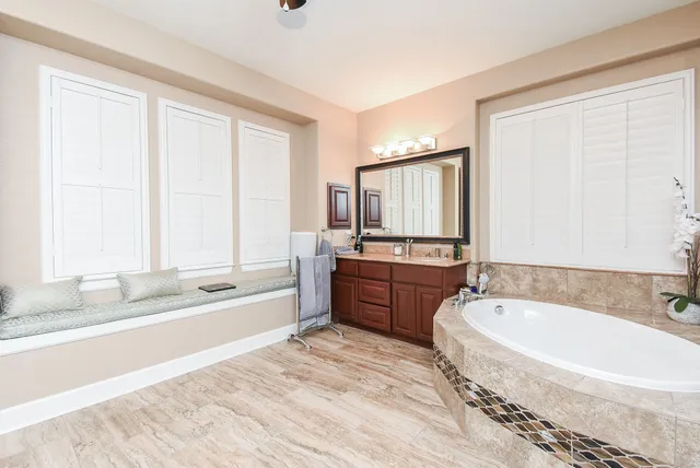 a spacious bathroom with a tub sink and mirror