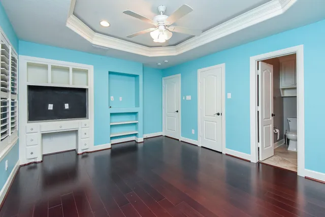 an empty room with wooden floor and a ceiling fan