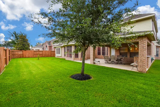 a view of a house with backyard and a tree