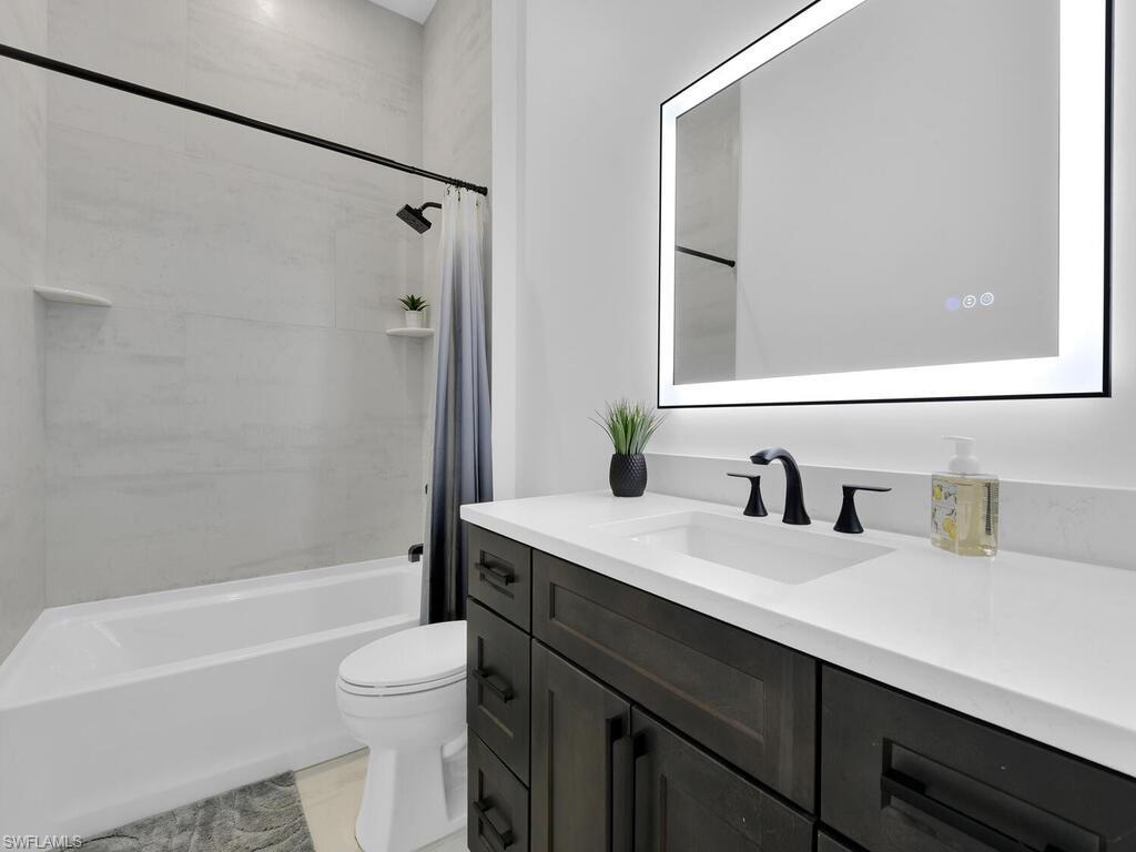 3475 3rd Avenue Southwest Naples, FL 34117 - Photo 21 of 49 a bathroom with a granite countertop sink toilet a mirror and shower