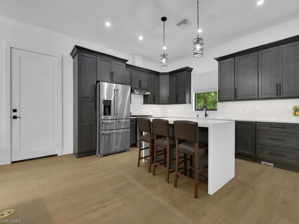 3475 3rd Avenue Southwest Naples, FL 34117 - Photo 27 of 49 a kitchen with kitchen island a cabinets a counter and a refrigerator