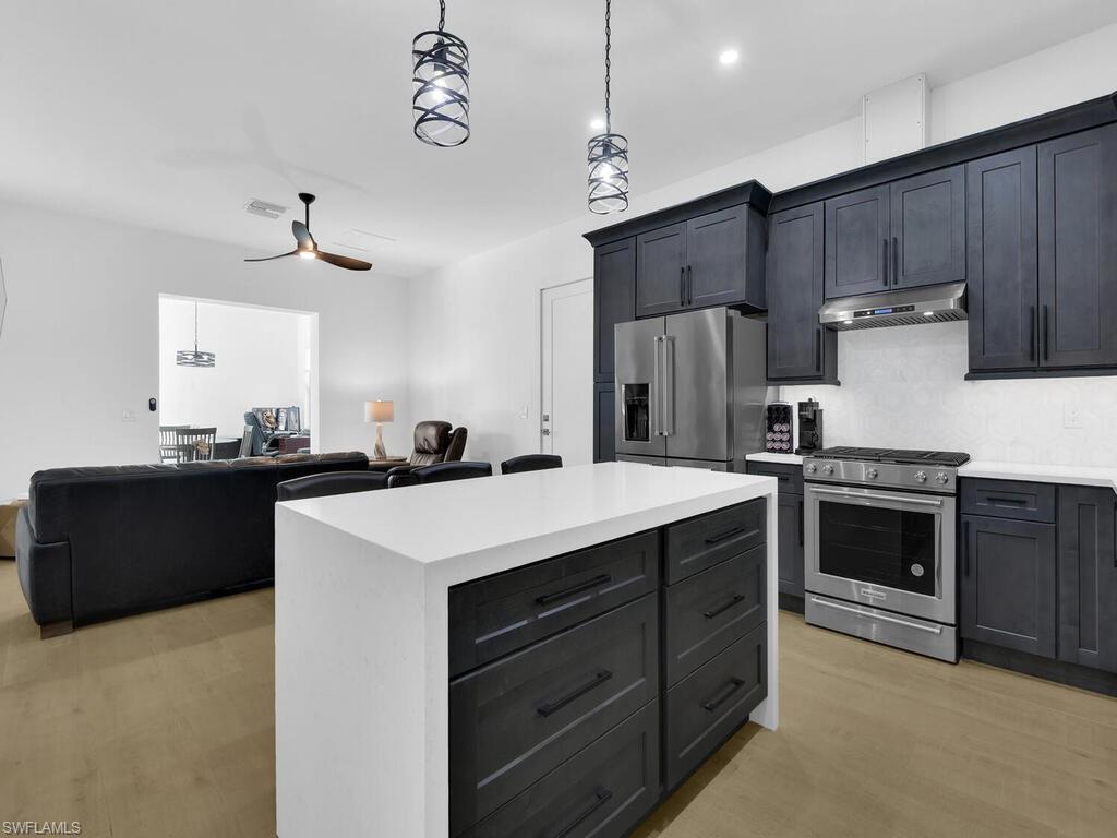 3475 3rd Avenue Southwest Naples, FL 34117 - Photo 28 of 49 a kitchen with kitchen island granite countertop a stove oven and a refrigerator with wooden floor