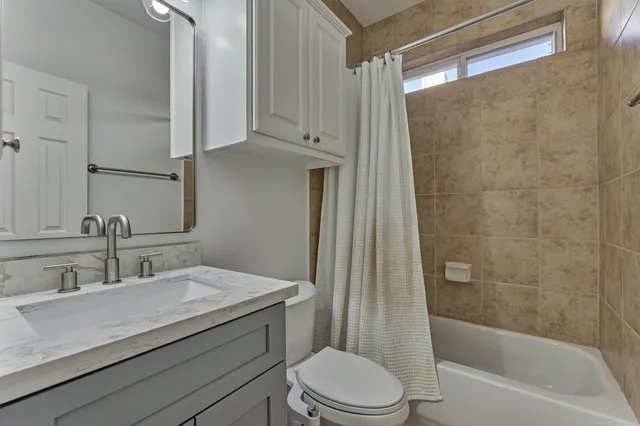 a bathroom with a granite countertop sink a toilet and shower