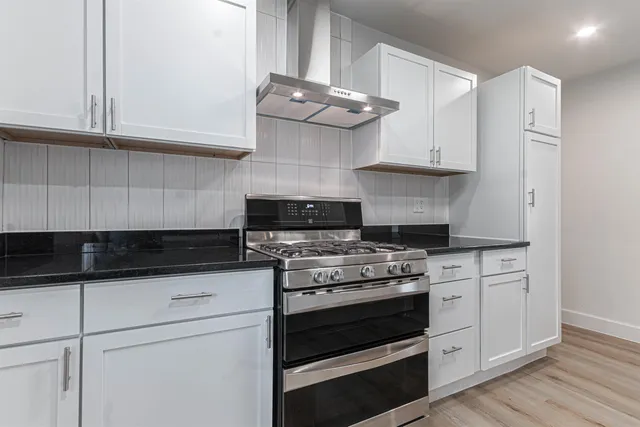 a kitchen with granite countertop a stove and a white cabinets