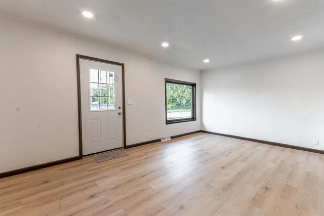 an empty room with wooden floor and windows