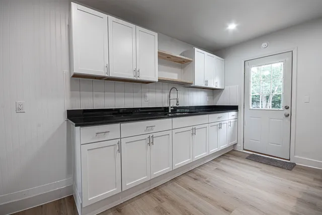 a kitchen with granite countertop white cabinets and white appliances