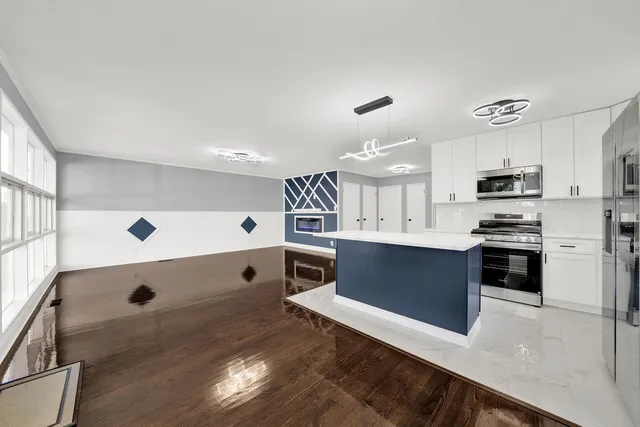 a large kitchen with stainless steel appliances a large counter top a stove a microwave and a refrigerator