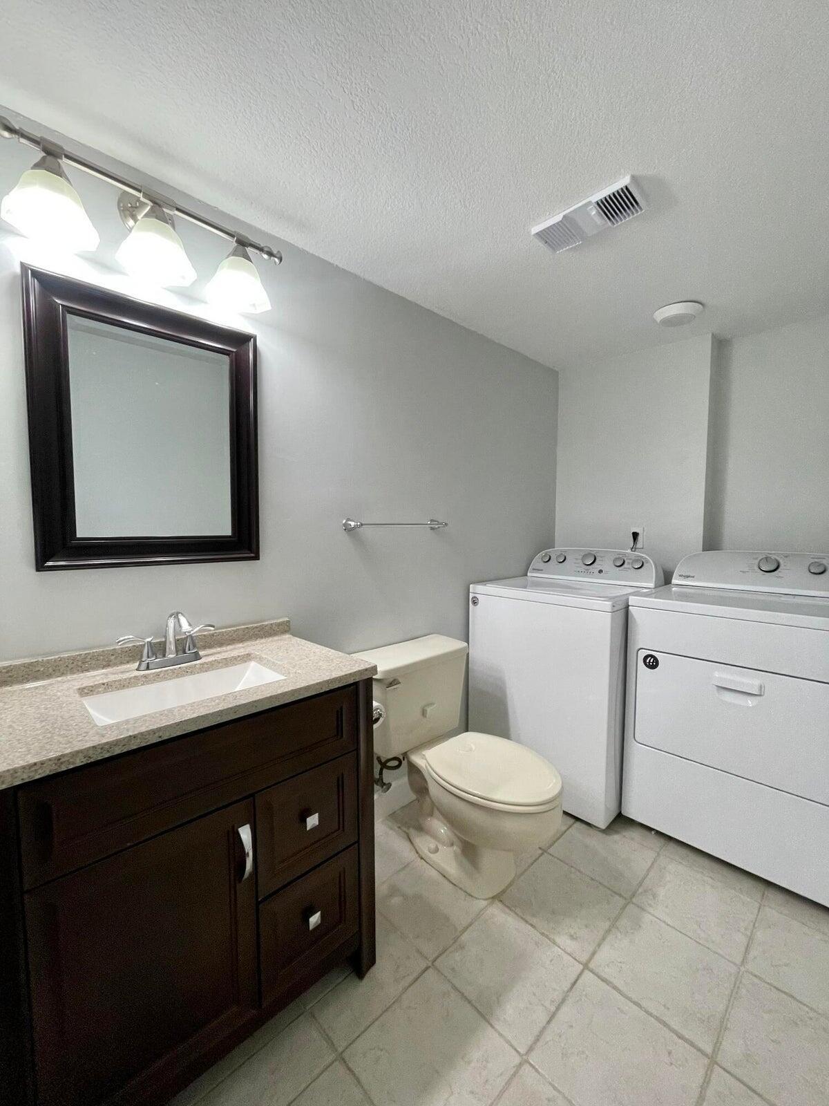 11551 Winchester Drive Palm Beach Gardens, FL 33410 - Photo 13 of 22 a bathroom with a toilet sink and mirror