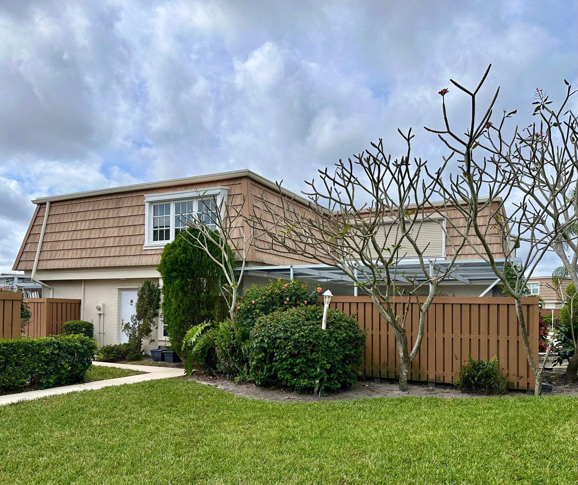 11551 Winchester Drive Palm Beach Gardens, FL 33410 - Photo 3 of 22 a view of backyard with potted plants and wooden fence