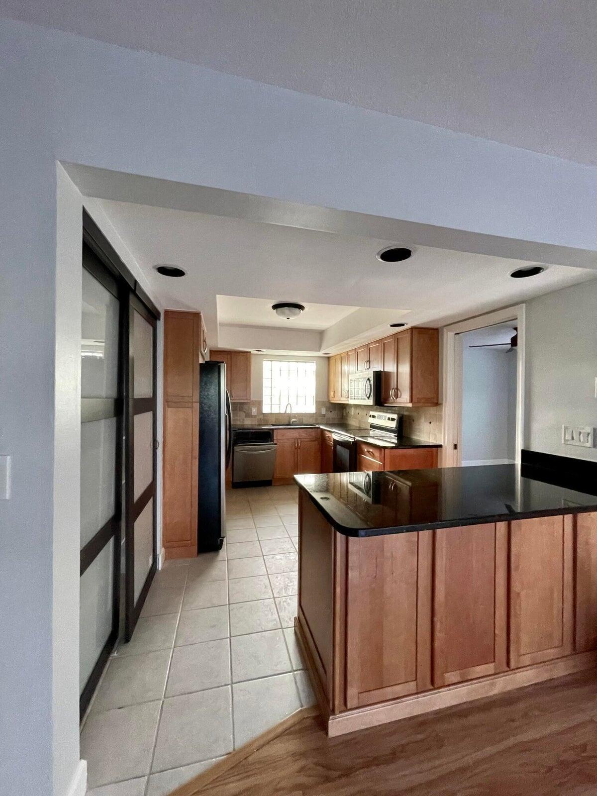 11551 Winchester Drive Palm Beach Gardens, FL 33410 - Photo 7 of 22 a kitchen with stainless steel appliances kitchen island granite countertop a refrigerator and a stove